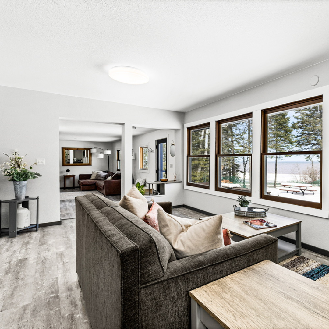 Open-plan cabin interior at Superior Shores with a spacious kitchen, dining area for six, and a plush sectional sofa near the fireplace